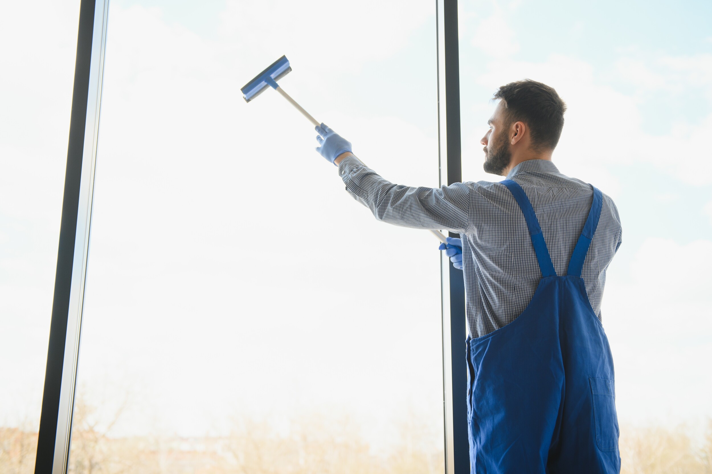Window Cleaning young man cleaning window in office 2023 09 21 05 11 19 utc